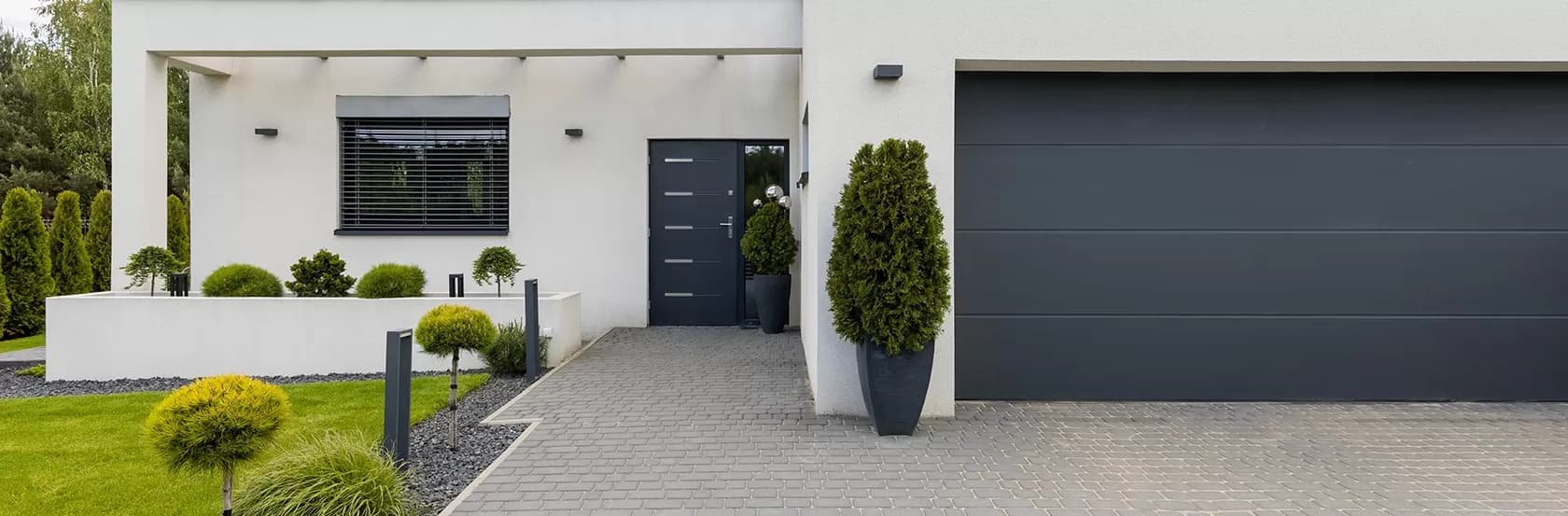 Nowoczesna, szara brama garażowa PAGEN Comfort przy wejściu do domu jednorodzinnego