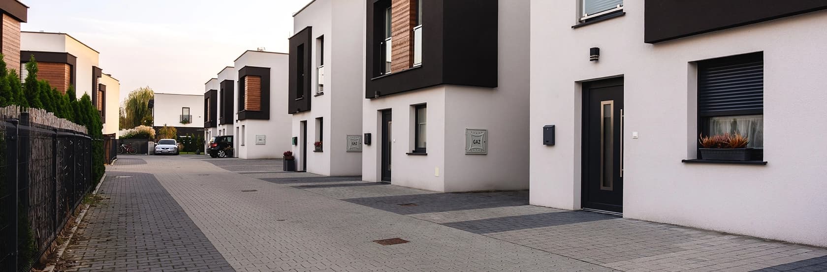 Nowoczesne, ciemne drzwi wejściowe PVC Modern Line w tle osiedla domów szeregowych